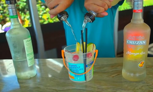 bartender pouring drinks into a voodoo buck with fruit