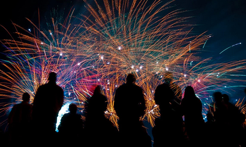silhouette of people in front of fireworks